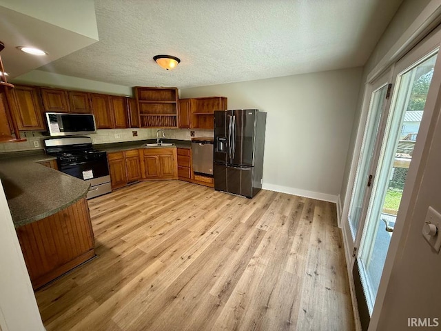1228 N Main St, Kewanna, IN 46939 - kitchen featuring appliances with stainless steel finishes, open shelves, dark countertops, brown cabinetry, and light wood-style flooring