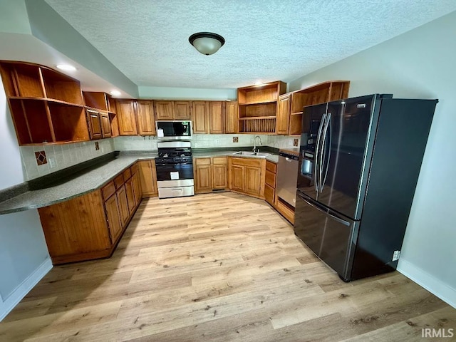 1228 N Main St, Kewanna, IN 46939 - kitchen featuring open shelves, stainless steel appliances, brown cabinetry, light wood-type flooring, and a textured ceiling