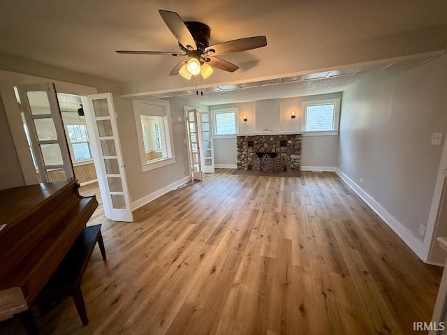 1228 N Main St, Kewanna, IN 46939 - unfurnished living room with wood finished floors, ceiling fan, and a stone fireplace