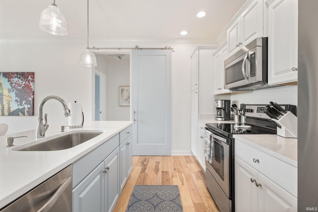 1219 Napoleon St Unit 217, South Bend, IN 46617 - kitchen with stainless steel appliances, light countertops, light wood-type flooring, white cabinets, and pendant lighting