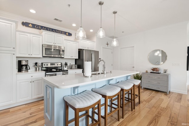 1219 Napoleon St Unit 217, South Bend, IN 46617 - kitchen with appliances with stainless steel finishes, crown molding, an island with sink, a kitchen bar, and white cabinets