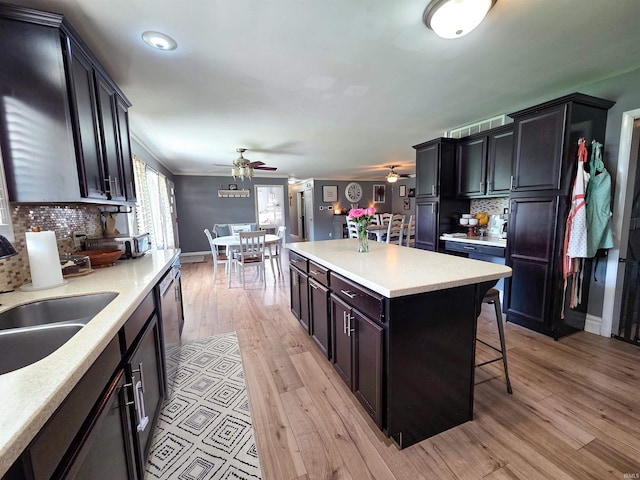 106 N Park Ave, Fowler, IN 47944 - kitchen with a ceiling fan, a breakfast bar area, tasteful backsplash, light countertops, and light wood-style floors