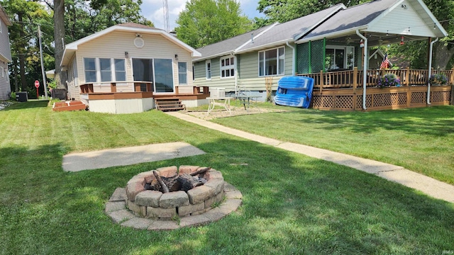 8121 N Tippecanoe Dr, Walkerton, IN 46574 - back of property with a deck, a fire pit, a lawn, crawl space, and a shingled roof