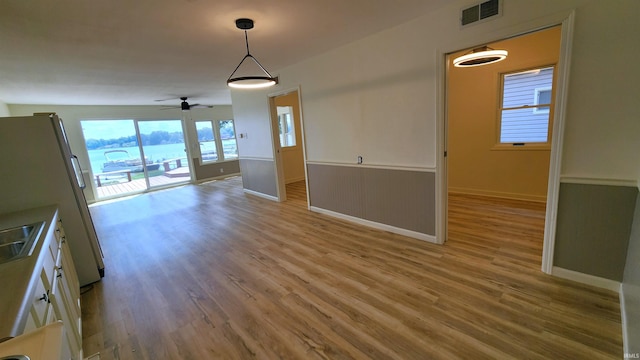 8121 N Tippecanoe Dr, Walkerton, IN 46574 - unfurnished dining area with wood finished floors, a ceiling fan, and a wainscoted wall