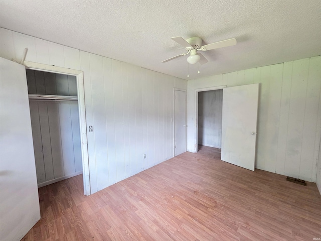 722 N Main St, Sullivan, IN 47882 - unfurnished bedroom with wood finished floors, a textured ceiling, a ceiling fan, and wood walls