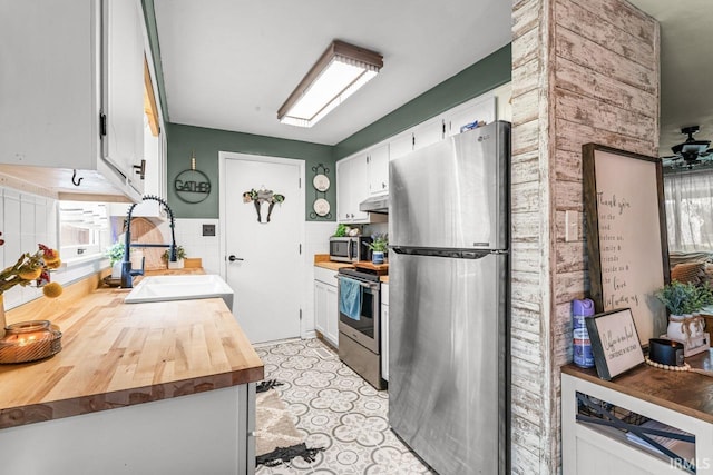 3331 Loral Dr, Anderson, IN 46013 - kitchen with appliances with stainless steel finishes, wooden counters, white cabinets, and under cabinet range hood