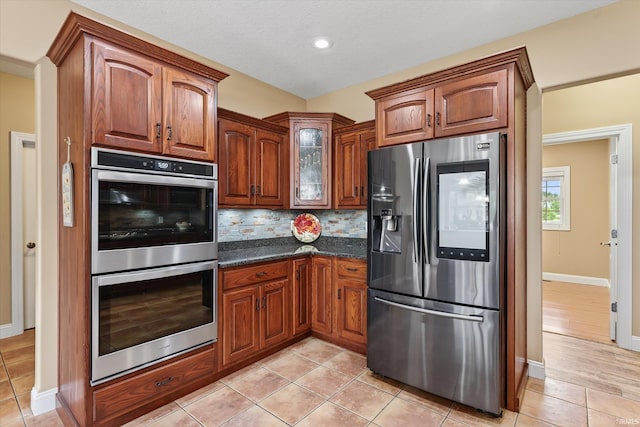 57907 Stone Creek Ct, Goshen, IN 46528 - kitchen with stainless steel appliances, tasteful backsplash, light tile patterned floors, glass insert cabinets, and brown cabinets