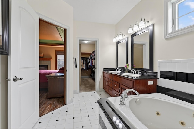 57907 Stone Creek Ct, Goshen, IN 46528 - bathroom featuring double vanity, a whirlpool tub, a fireplace, and a spacious closet