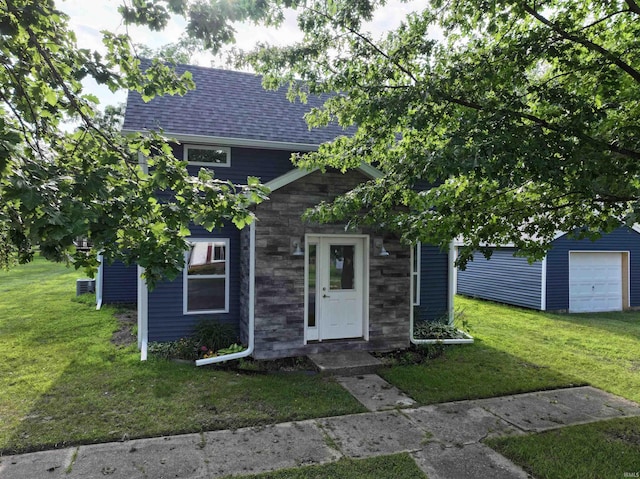 719 N Hathaway St, Winamac, IN 46996 - view of front of house with a front yard, a shingled roof, and stone siding