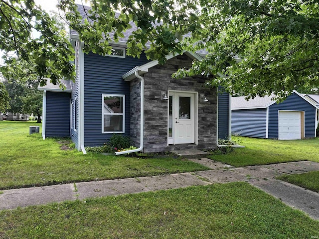 719 N Hathaway St, Winamac, IN 46996 - view of front of home featuring a front lawn, stone siding, an outdoor structure, and a garage