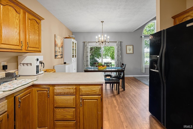 1709 Stonegate Cir, Lafayette, IN 47909 - kitchen featuring black fridge with ice dispenser, a peninsula, a chandelier, brown cabinetry, and a textured ceiling