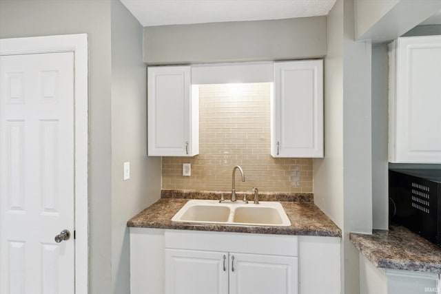 55310 Moss Rd, South Bend, IN 46628 - kitchen with backsplash, dark countertops, and white cabinetry