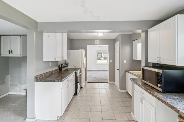 55310 Moss Rd, South Bend, IN 46628 - kitchen featuring stainless steel appliances, white cabinets, light tile patterned floors, and dark countertops
