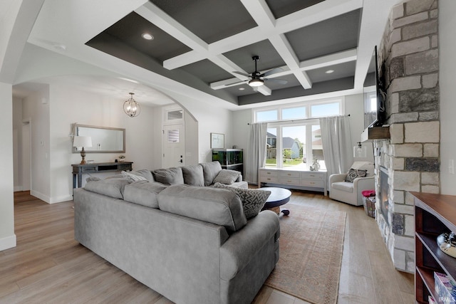 1419 Codorna Cv, Fort Wayne, IN 46804 - living room featuring coffered ceiling, arched walkways, a stone fireplace, a ceiling fan, and light wood finished floors