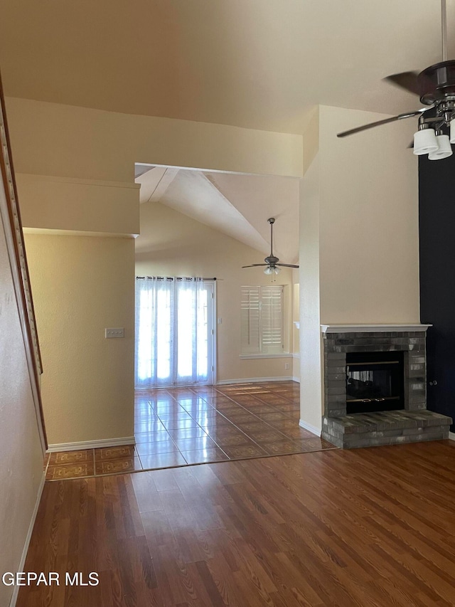 unfurnished living room featuring ceiling fan, hardwood / wood-style flooring, lofted ceiling, and a stone fireplace