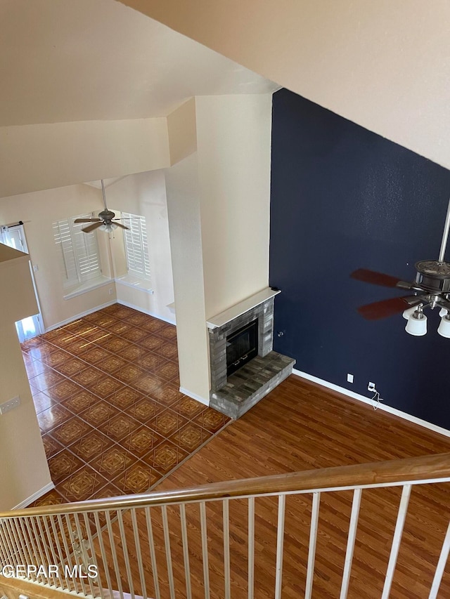 unfurnished living room with dark wood-type flooring, ceiling fan, and a fireplace