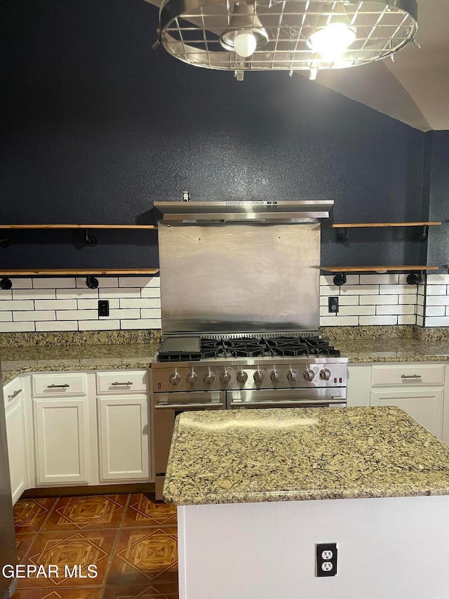 kitchen with decorative backsplash, white cabinets, light stone counters, and exhaust hood