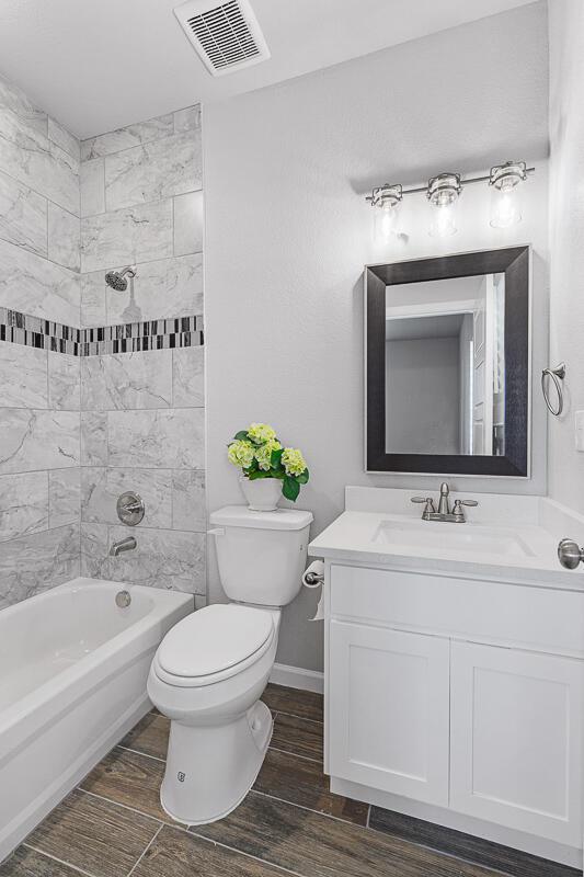 full bathroom with wood-type flooring, vanity, toilet, and tiled shower / bath