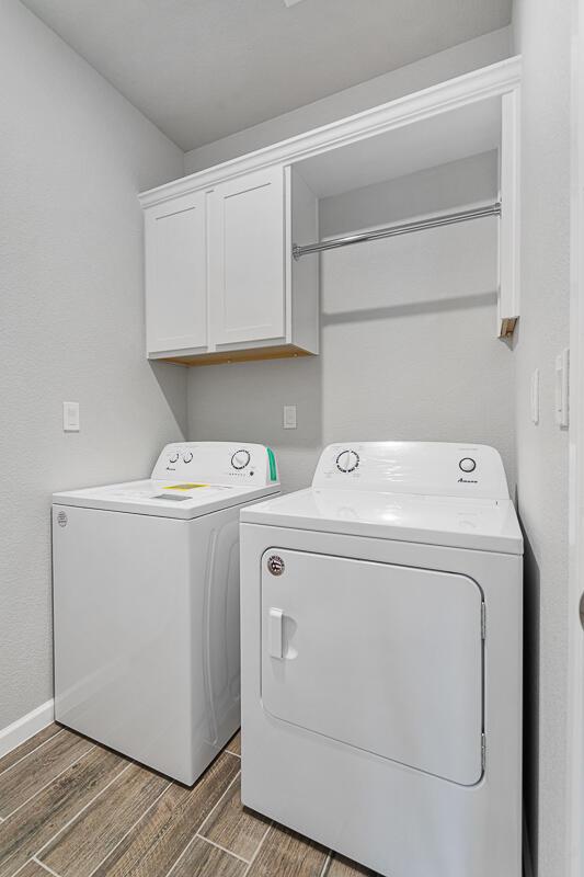 clothes washing area with cabinets, independent washer and dryer, and dark hardwood / wood-style floors