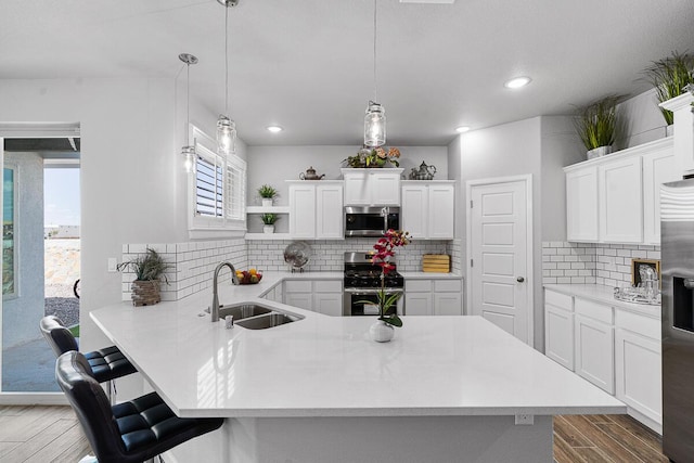 kitchen featuring white cabinets, stainless steel appliances, hanging light fixtures, and sink