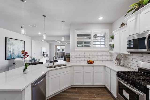 kitchen with appliances with stainless steel finishes, dark hardwood / wood-style flooring, sink, decorative light fixtures, and white cabinets