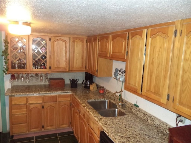 kitchen featuring a textured ceiling, dark tile floors, sink, and light stone counters