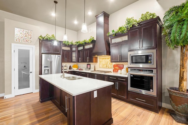 2425 Cesar Cordova Pl, El Paso, TX 79938 - kitchen featuring pendant lighting, appliances with stainless steel finishes, custom range hood, light hardwood / wood-style floors, and tasteful backsplash