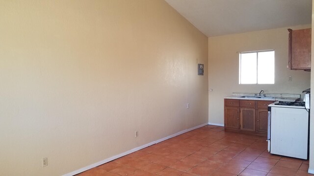 kitchen with light tile flooring, white stove, and sink