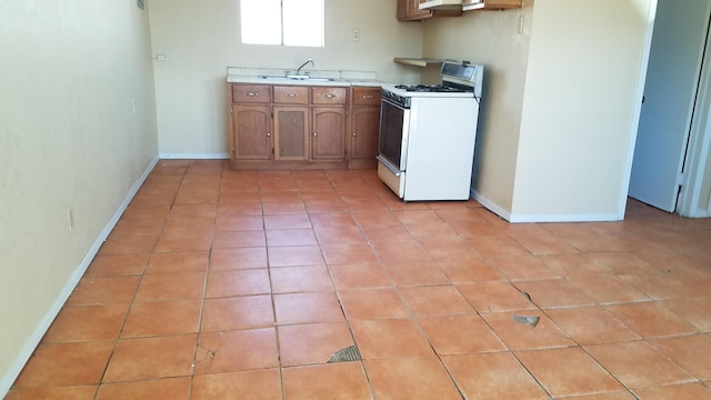 kitchen featuring light tile floors, white gas range, and sink