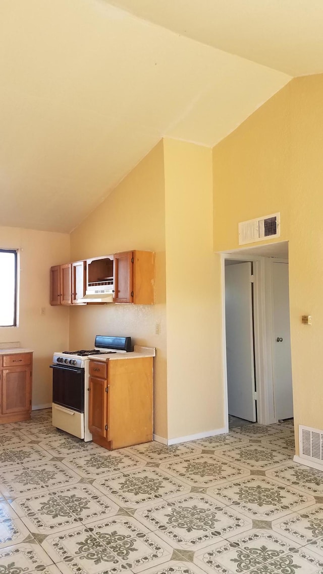 kitchen with light tile floors, white gas range oven, and high vaulted ceiling