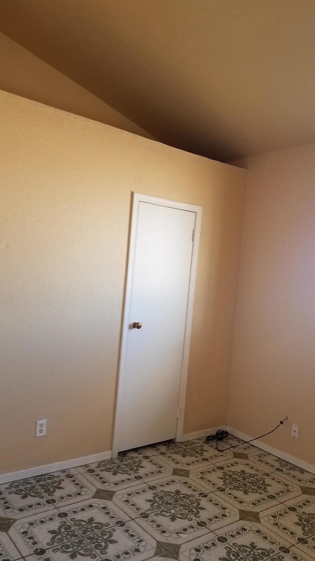 empty room with lofted ceiling and tile floors