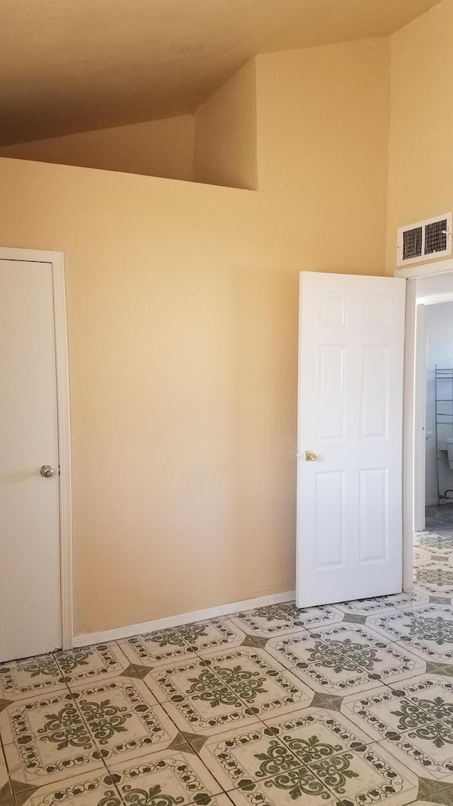 unfurnished room with tile flooring and vaulted ceiling