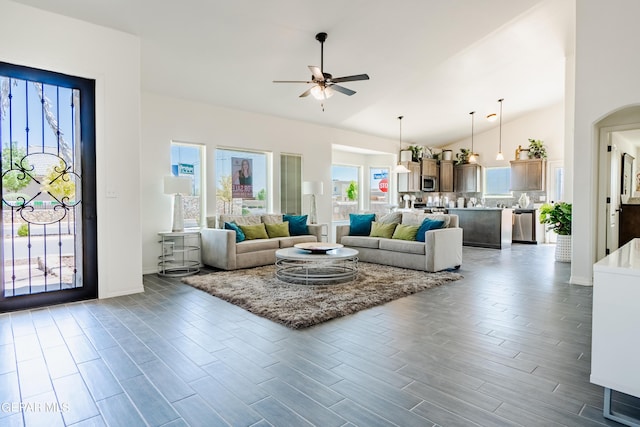 living room with wood finished floors, high vaulted ceiling, ceiling fan, and arched walkways