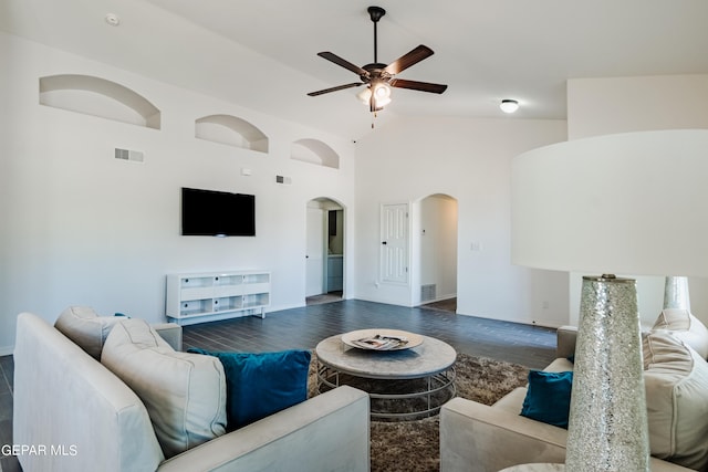living area featuring visible vents, high vaulted ceiling, dark wood-type flooring, a ceiling fan, and arched walkways