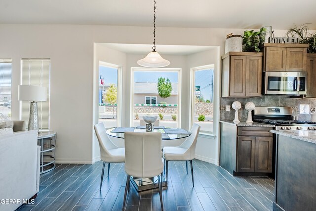 kitchen with light stone counters, dark hardwood / wood-style flooring, stainless steel appliances, and decorative light fixtures