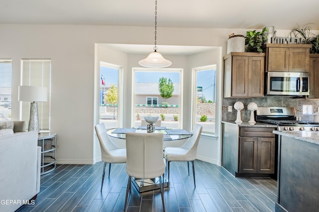 kitchen with tasteful backsplash, appliances with stainless steel finishes, baseboards, and wood tiled floor