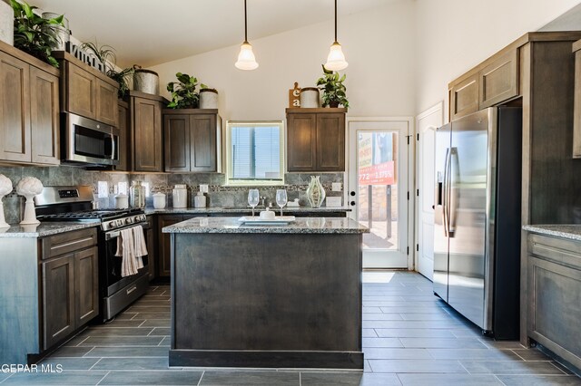 kitchen with light stone countertops, stainless steel appliances, hanging light fixtures, and a center island