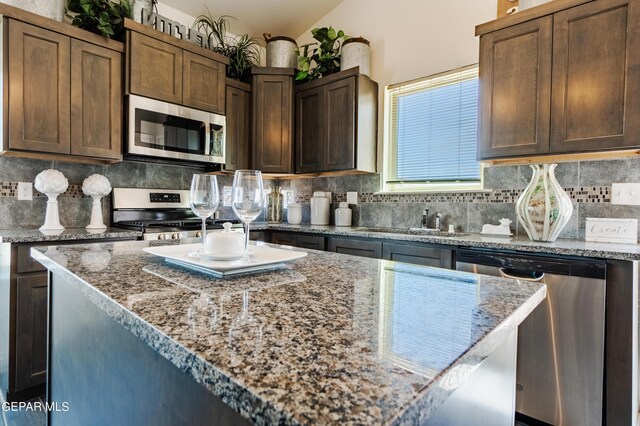 kitchen with appliances with stainless steel finishes, decorative backsplash, dark brown cabinets, and light stone counters