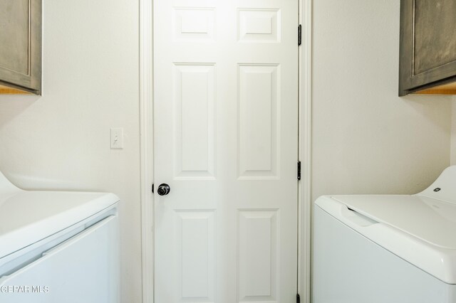 clothes washing area featuring cabinets and washing machine and dryer