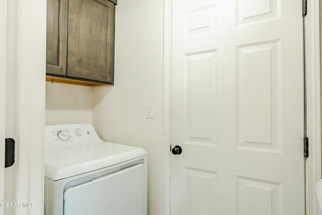 clothes washing area featuring washer / clothes dryer and cabinets