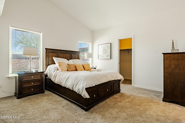 bedroom featuring light colored carpet, a closet, a spacious closet, and high vaulted ceiling