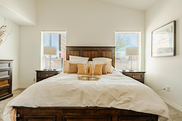 bedroom with light colored carpet, vaulted ceiling, and multiple windows