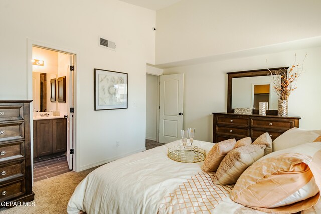 bedroom featuring a towering ceiling, dark hardwood / wood-style floors, and ensuite bathroom