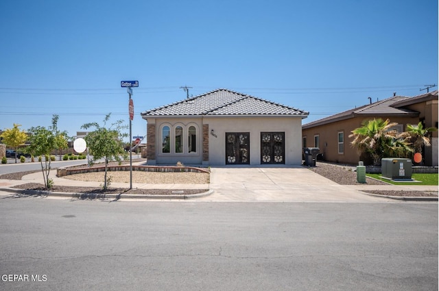 mediterranean / spanish home featuring central AC, stucco siding, concrete driveway, a garage, and a tile roof