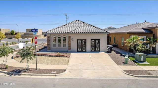 mediterranean / spanish-style house with stucco siding, french doors, and a tile roof