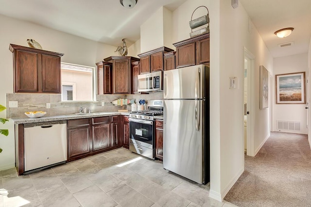 kitchen with sink, tasteful backsplash, light colored carpet, dark brown cabinets, and stainless steel appliances