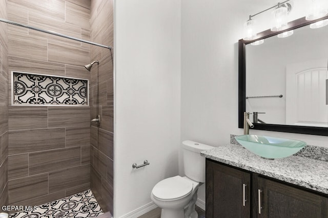 bathroom with vanity, toilet, and tiled shower