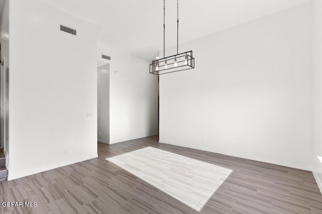 spare room featuring a notable chandelier and light wood-type flooring