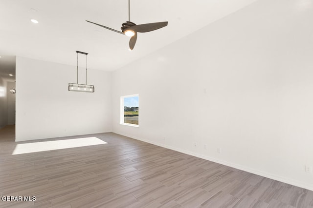 unfurnished room with light hardwood / wood-style flooring, a high ceiling, and ceiling fan