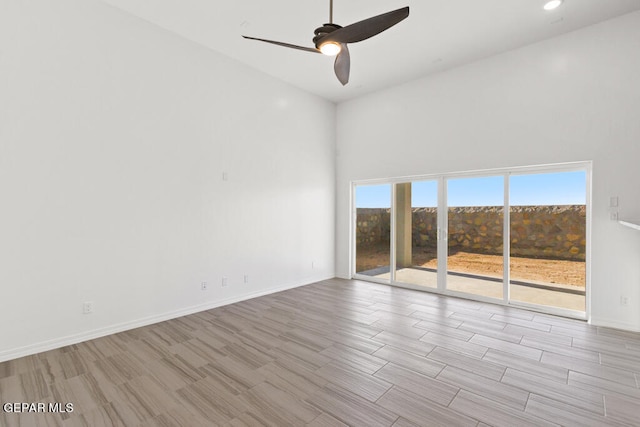 empty room featuring high vaulted ceiling, ceiling fan, and light wood-type flooring